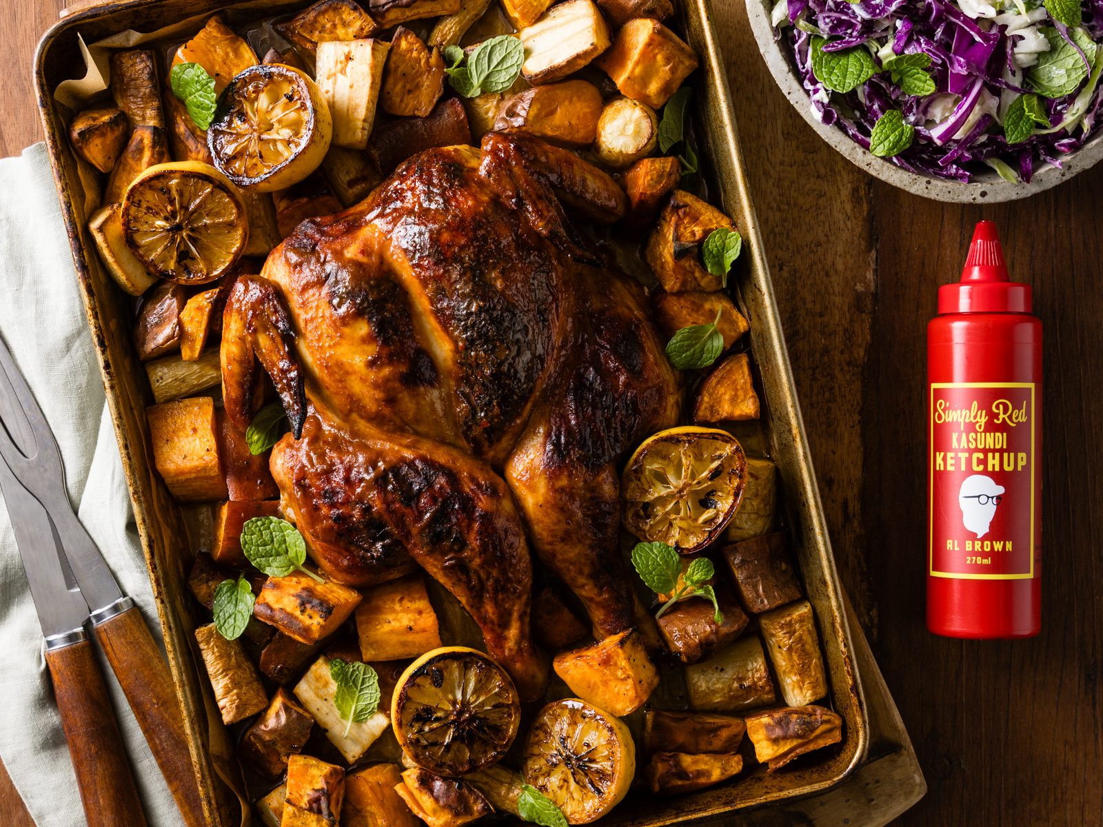 Al Brown's Kasundi Roast Chicken 1 Al Browns Kasundi Roast Chicken on a table with roasted vegetables and a side of slaw.