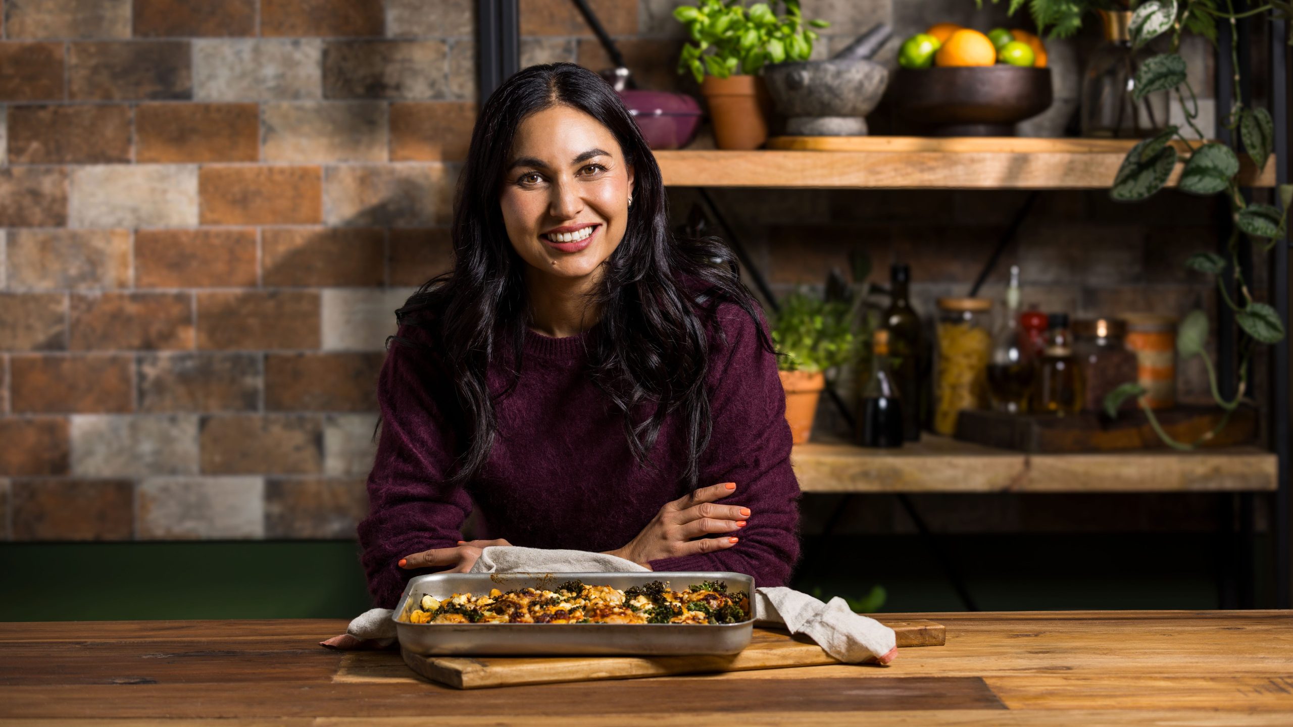 Nadia Lim standing in a kitchen with a My Food Bag meal kit recipe on the bench.